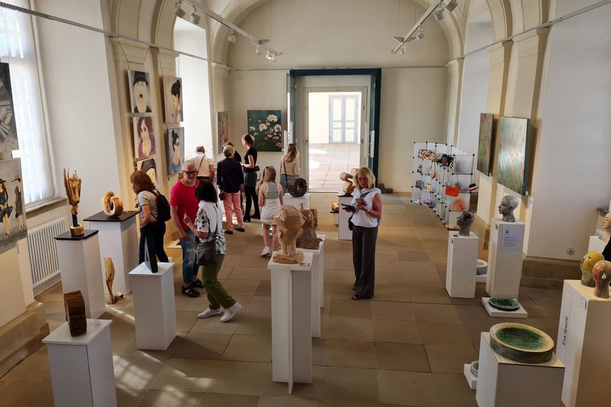 Historischer Ausstellungssaal, Kunstwerke an den Wänden und auf Sockeln, dazwischen Besucher